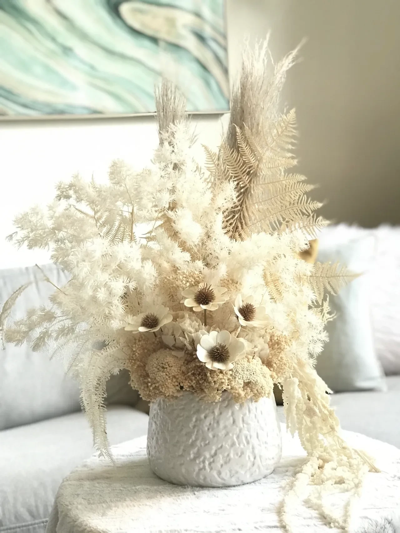 Dried flowers and ferns in white ceramic vase